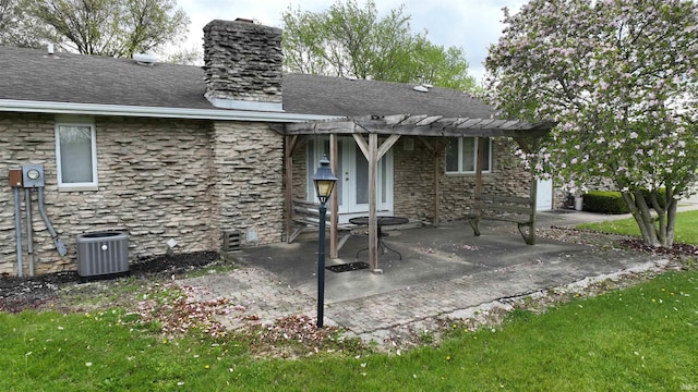 back of house with a pergola, stone siding, a chimney, central AC unit, and a patio area
