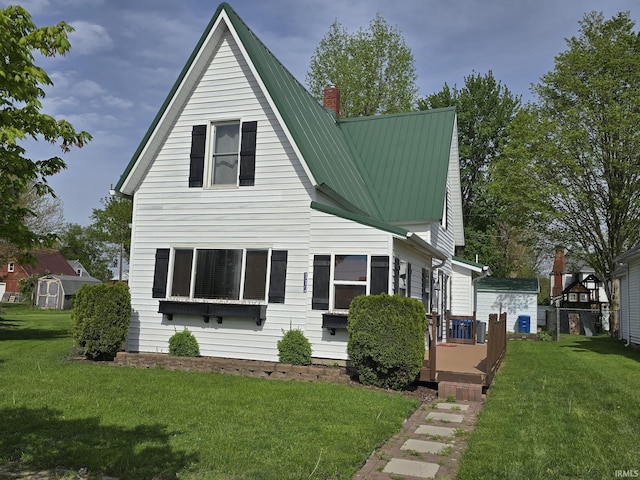 bungalow-style home with a chimney, a front yard, and metal roof
