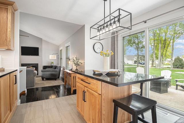 kitchen with vaulted ceiling, a breakfast bar, a wealth of natural light, and dark countertops