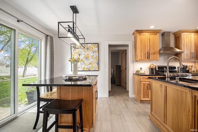 kitchen featuring a center island, dark countertops, a kitchen breakfast bar, and wall chimney range hood