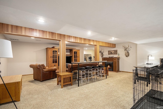 carpeted living area with baseboards, a lit fireplace, recessed lighting, and visible vents