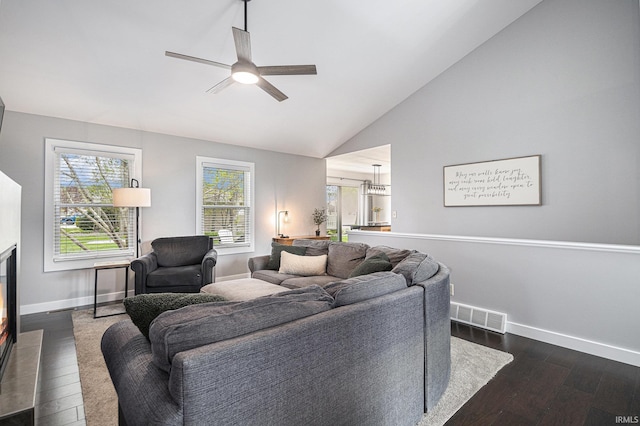 living area featuring dark wood-style flooring, a ceiling fan, baseboards, vaulted ceiling, and visible vents