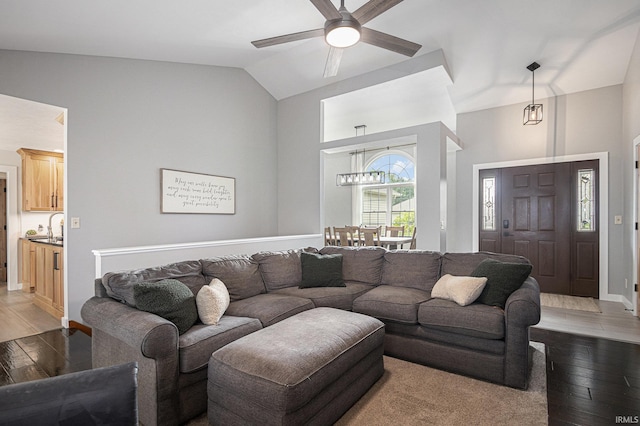 living area featuring baseboards, a ceiling fan, high vaulted ceiling, and light wood-style flooring
