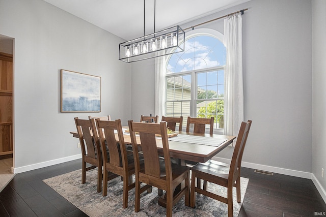 dining space featuring baseboards, visible vents, dark wood-type flooring, and a chandelier