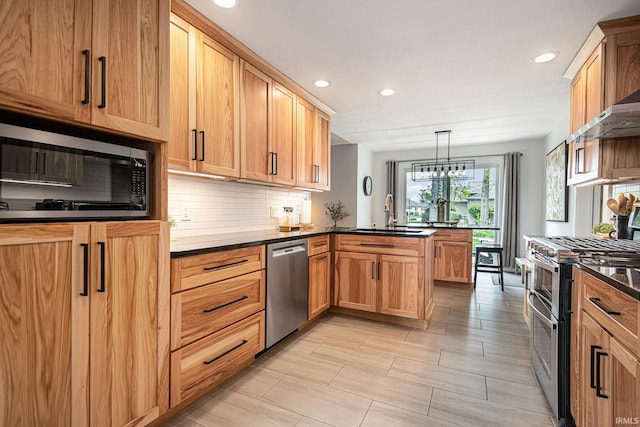 kitchen with backsplash, stainless steel appliances, a sink, and a peninsula