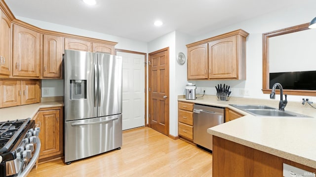 kitchen featuring appliances with stainless steel finishes, a sink, light countertops, light wood-style flooring, and recessed lighting