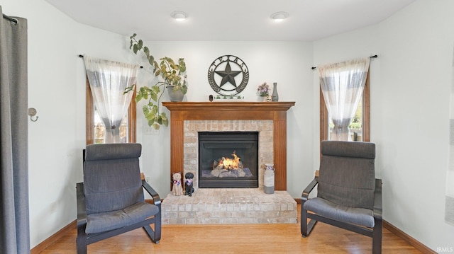 sitting room featuring baseboards, a brick fireplace, and wood finished floors