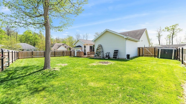 rear view of property featuring a fenced backyard, a wooden deck, and a lawn