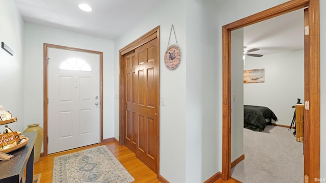 foyer entrance with baseboards, ceiling fan, and light wood finished floors