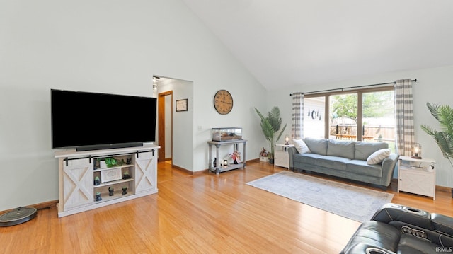 living room with baseboards, high vaulted ceiling, and light wood-style flooring