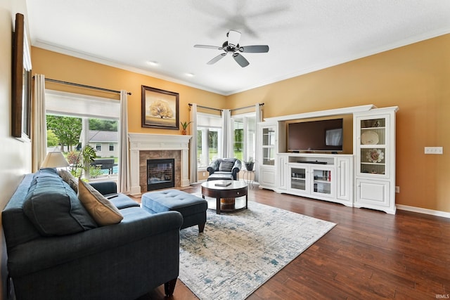 living area featuring ornamental molding, ceiling fan, dark wood-style floors, a tile fireplace, and baseboards