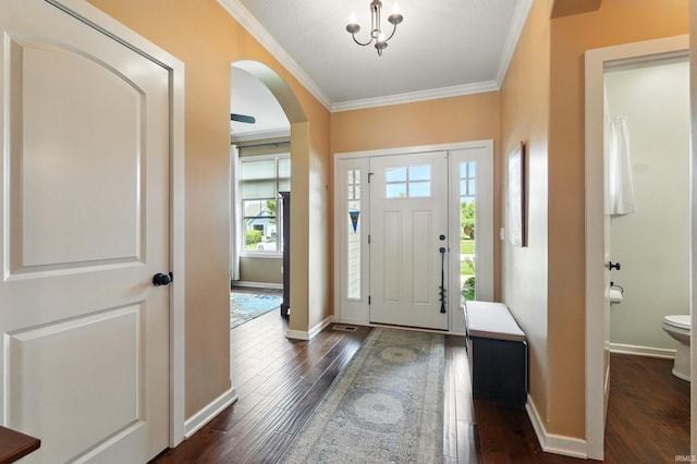 entryway featuring arched walkways, dark wood-style floors, crown molding, and baseboards