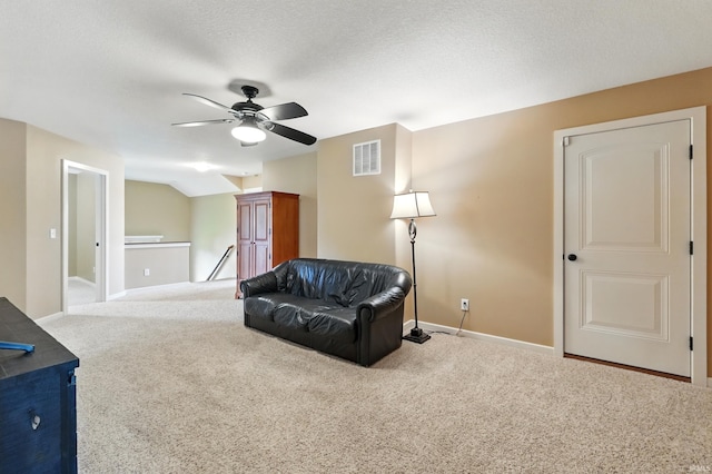 living area with ceiling fan, carpet floors, an upstairs landing, baseboards, and a textured ceiling