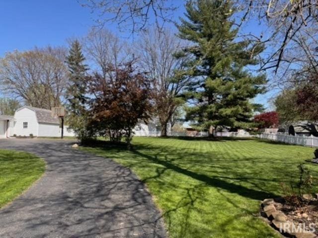 exterior space with a garage, fence, a lawn, and aphalt driveway