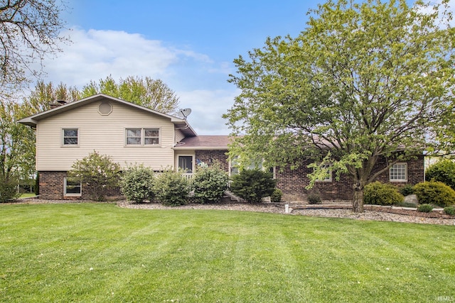 tri-level home featuring a front lawn and brick siding