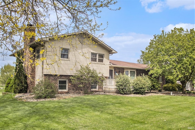 view of front of property with a chimney, a front yard, and brick siding