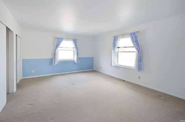 unfurnished bedroom featuring carpet floors, baseboards, and visible vents