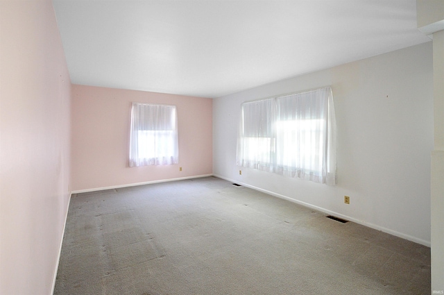 carpeted spare room with visible vents and baseboards