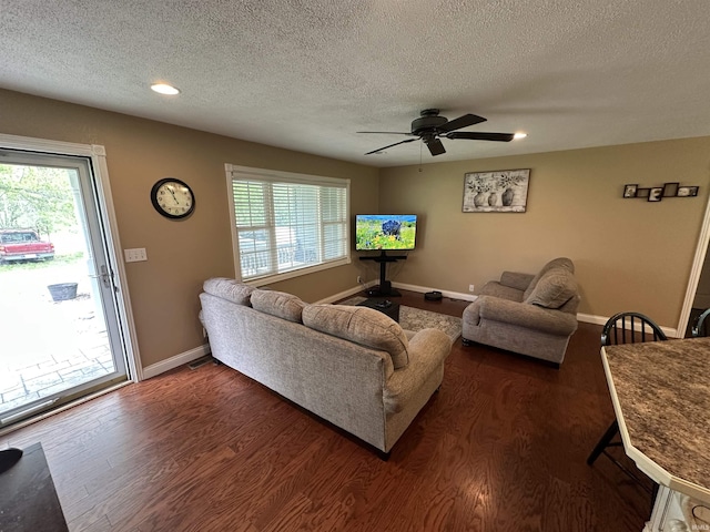 living room featuring a textured ceiling, dark wood-type flooring, and a ceiling fan
