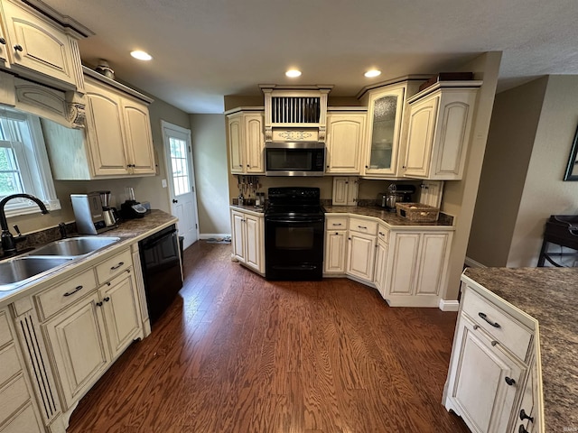 kitchen with glass insert cabinets, baseboards, a sink, black appliances, and dark wood-style floors
