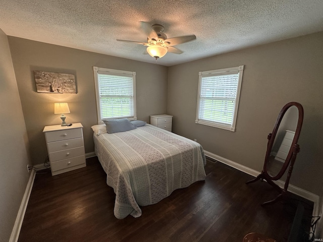 bedroom with dark wood-style flooring, a textured ceiling, baseboards, and multiple windows