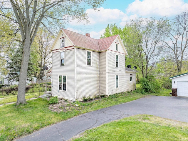 view of home's exterior with a yard, driveway, a chimney, and a garage