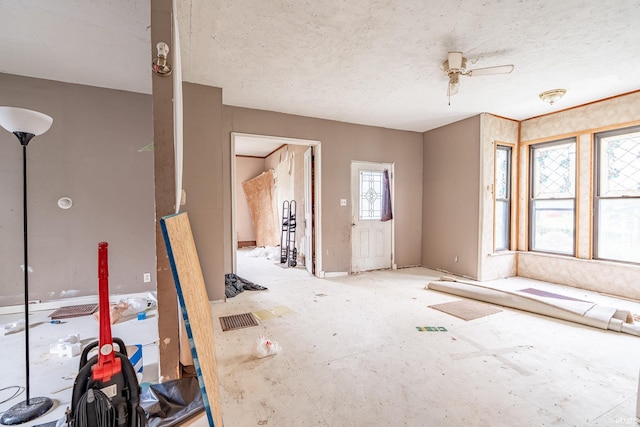 unfurnished living room featuring ceiling fan and a textured ceiling