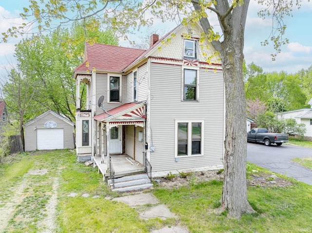 victorian home with a garage, a chimney, a front yard, an outbuilding, and driveway