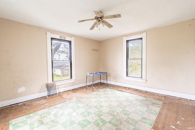 empty room with baseboards, a wealth of natural light, ceiling fan, and wood finished floors