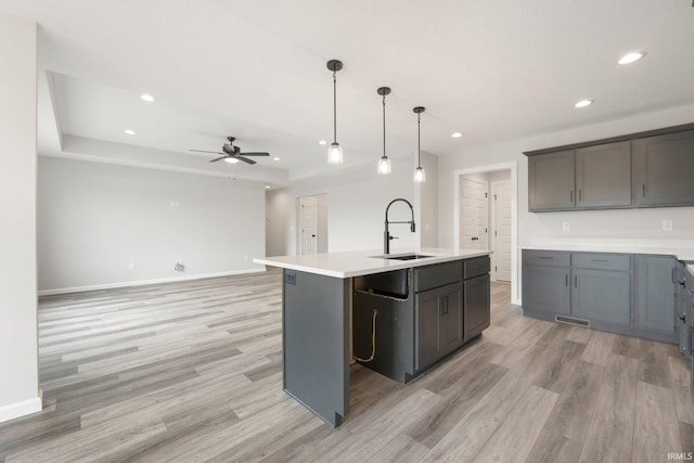 kitchen featuring light wood-type flooring, baseboards, a ceiling fan, and a sink