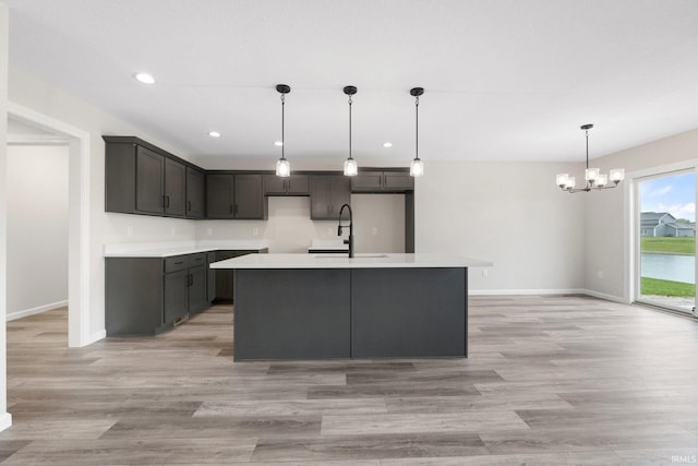 kitchen featuring a sink, recessed lighting, a notable chandelier, baseboards, and light wood-style floors