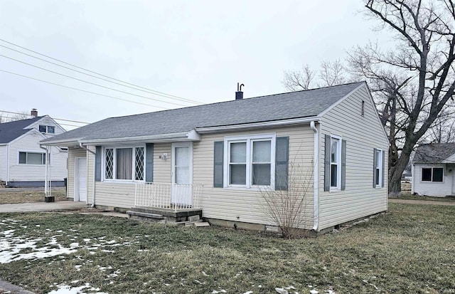 view of front of house featuring roof with shingles and a front lawn