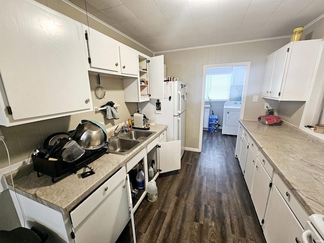 kitchen with a sink, washer / dryer, dark wood finished floors, decorative backsplash, and white cabinets