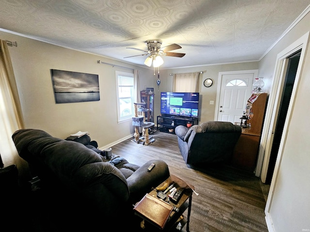 living area featuring baseboards, crown molding, ceiling fan, and wood finished floors