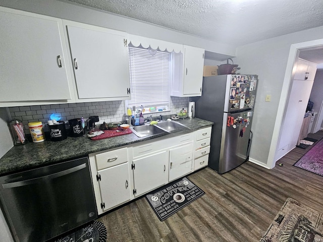 kitchen featuring a sink, tasteful backsplash, freestanding refrigerator, dishwashing machine, and dark wood-type flooring