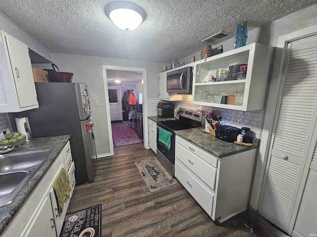 kitchen with dark countertops, white cabinetry, dark wood-style flooring, appliances with stainless steel finishes, and decorative backsplash