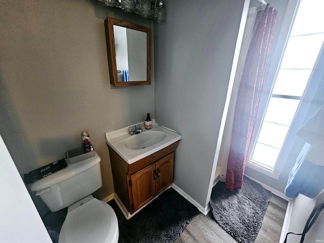 bathroom with toilet, wood finished floors, a shower with curtain, baseboards, and vanity