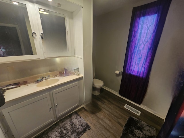bathroom featuring toilet, wood finished floors, vanity, visible vents, and baseboards