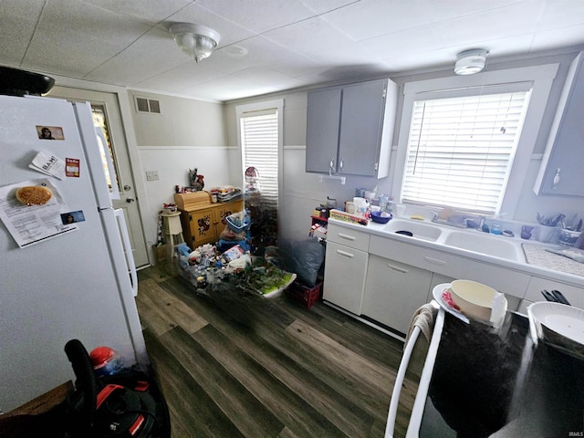 kitchen featuring freestanding refrigerator, visible vents, a sink, light countertops, and dark wood-style floors