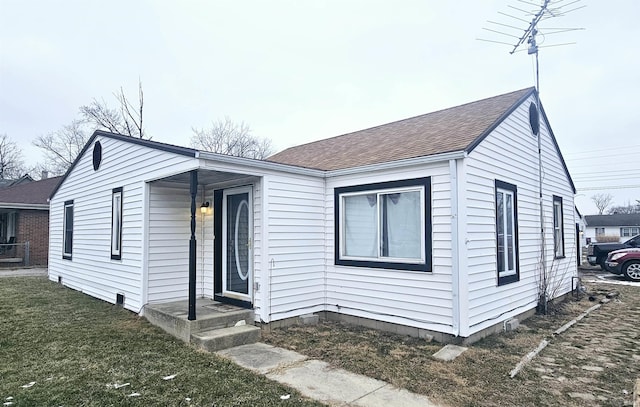 view of front facade featuring roof with shingles and a front lawn