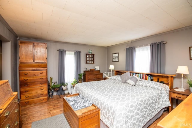 bedroom featuring multiple windows, light wood-style flooring, and ornamental molding