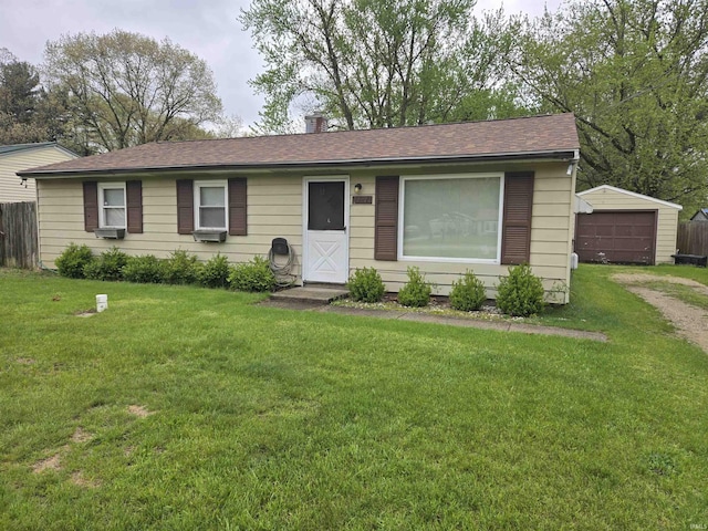 ranch-style home featuring roof with shingles, fence, an outbuilding, and a front yard