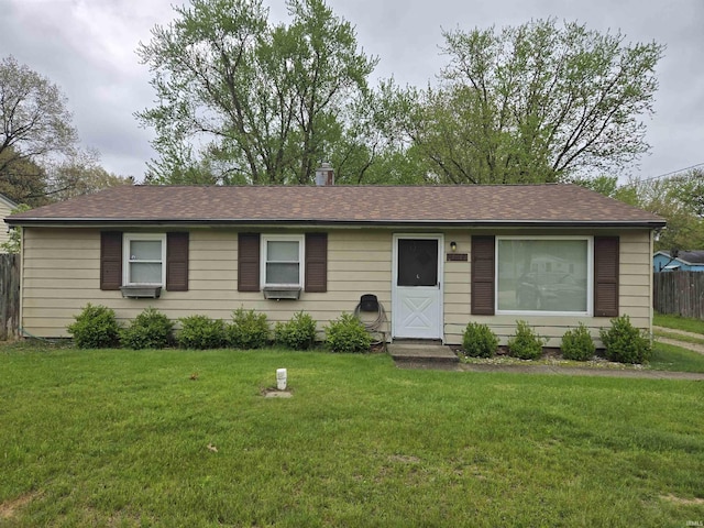 single story home with a shingled roof, fence, and a front yard