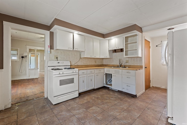 kitchen with white appliances, a sink, backsplash, light countertops, and white cabinets