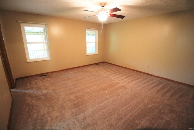 empty room featuring a ceiling fan, a wealth of natural light, and carpet