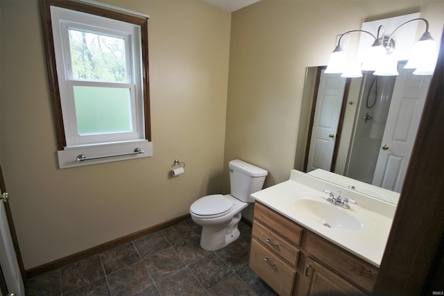 bathroom featuring vanity, toilet, baseboards, and stone finish flooring