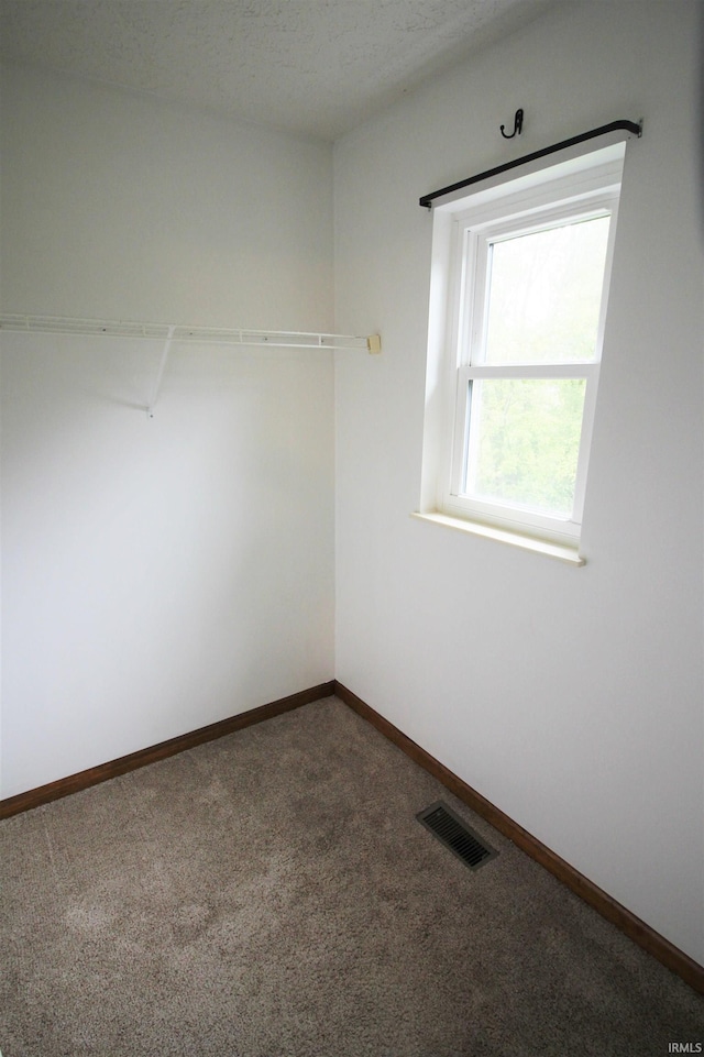 empty room featuring visible vents, baseboards, and dark colored carpet