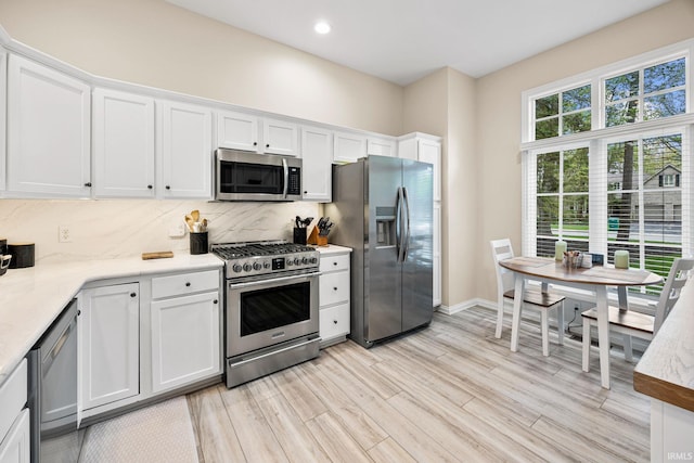 1611 Rockwood Ln, Mishawaka, IN 46545 - kitchen with light wood finished floors, tasteful backsplash, white cabinetry, and appliances with stainless steel finishes
