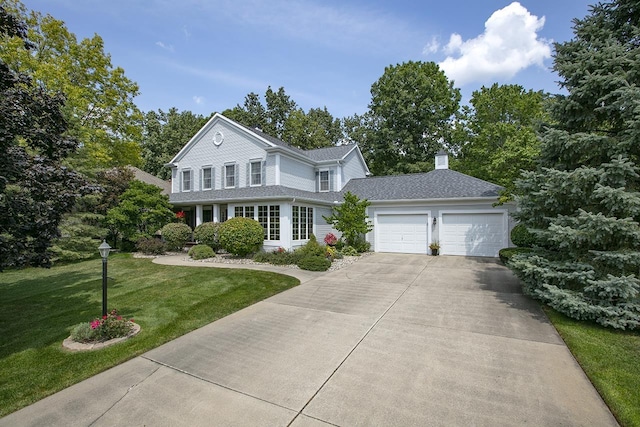 traditional-style home featuring a garage, a front lawn, a chimney, and driveway