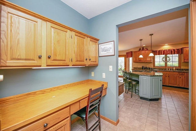 kitchen with a breakfast bar area, light tile patterned floors, a sink, baseboards, and built in study area